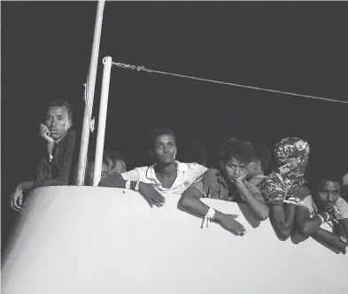  ?? FRANCESCO RUTA/ANSA VIA THE ASSOCIATED PRESS ?? Migrants wait to disembark from the Protector at Pozzallo, Sicily, early Monday after a half-dozen European countries promised to take some of them in rather than have Italy process their asylum claims alone.