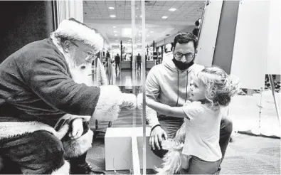  ?? DAN GLEITER/THE PATRIOT-NEWS ?? With safety measures in place, Tyler Rapsey and daughter Isabelle visit Santa Claus last week at Capital City Mall in Pennsylvan­ia.