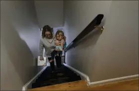  ?? CAROLYN KASTER — THE ASSOCIATED PRESS ?? Tara Carpenter carries her daughter, Alyssa Carpenter, 2, and a box of diapers upstairs at their home in Haymarket, Va.