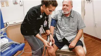  ?? Michael Wyke ?? RN Abbie Ives records Randall Boeller’s vital signs during a follow-up visit to the cancer treatment center at Houston Methodist The Woodlands Hospital.