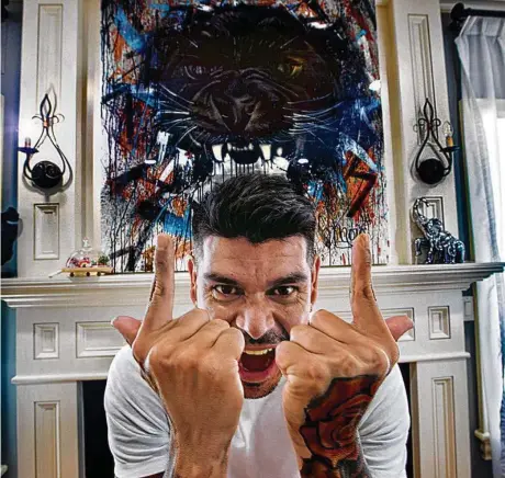  ?? STAN GROSSFELD/GLOBE STAFF ?? The Revolution’s Gustavo Bou shows off his famous panther sign under a piece of artwork that he commission­ed from a fan.