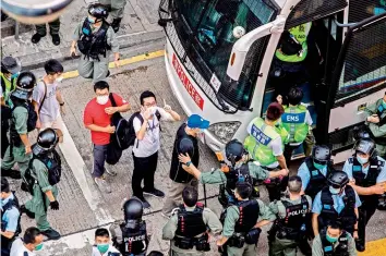  ?? — AFP ?? A man (centre L) gestures the protest slogan “Five demands and not one less” as he is arrested and led onto a bus by police during a protest against China’s planned national security law in Hong Kong on Sunday.