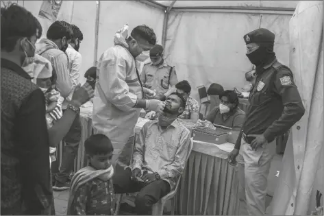  ?? PHOTO BY ALTAF QADRI/ASSOCIATED PRESS ?? A HEALTH WORKER TAKES A NASAL SWAB sample of a passenger to test for COVID-19 at a bus terminal in New Delhi, India.