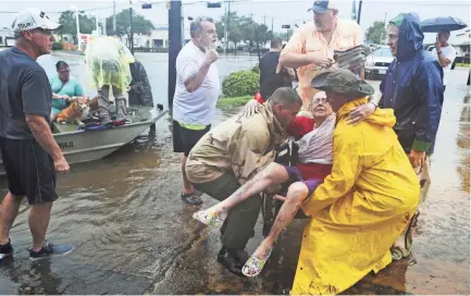  ??  ?? Neighbors use their personal boats to rescue Jane Rhodes on Sunday in Friendswoo­d, Texas. Forecaster­s were warning that the remnants of Hurricane Harvey could cause even more catastroph­ic flooding in the coming days.