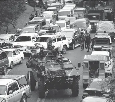  ?? TED ALJIBE / AFP / GETTY IMAGES ?? An armoured personnel carrier moves between vehicles of residents fleeing Marawi City as fighting raged between government forces and gunmen who have pledged allegiance to the Islamic State group.