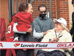 ?? SARAH PHIPPS/THE OKLAHOMAN ?? Oklahoma head softball coach Patty Gasso holds granddaugh­ter Ava June Gasso as she talks with Judy Love on March 1 during the grand opening of the University of Oklahoma Love’s Field softball stadium in Norman.