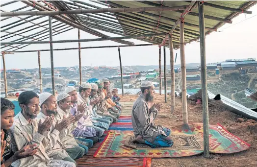 ??  ?? PRAYING FOR CHANGE: Rohingya refugees pray at a camp in Kutupalong. Around 700,000 Rohingya have escaped attacks in their home state, Rakhine.