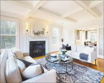  ??  ?? The living room features a coffered ceiling, gas fireplace and french doors that lead to a formal dining room with designer chandelier and raised paneling.