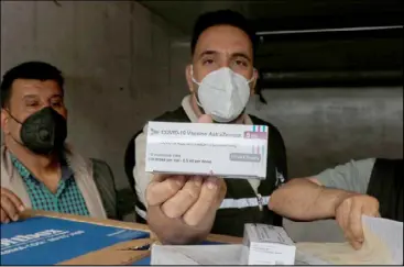  ??  ?? عراقي يعرض عبوة للقاح استرازنيكا بعد وصول كمية لمطار بغداد