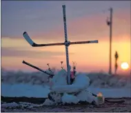  ?? JONATHAN HAYWARD/THE CANADIAN PRESS ?? The sun rises across the Prairies, revealing a cross made out of hockey sticks at a makeshift memorial at the intersecti­on where the Humboldt Broncos’ bus collided with a transport truck on April 6 while the Junior A hockey team was headed to Nipawin,...