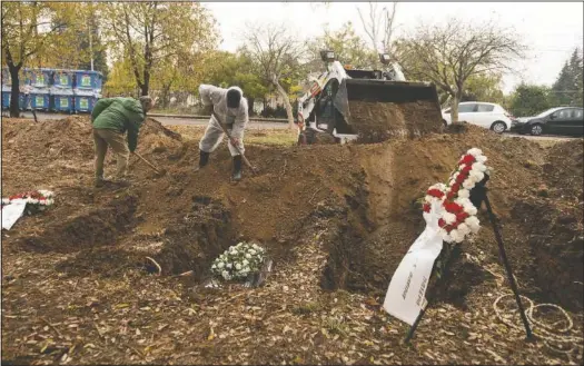  ??  ?? Workers shovel soil over a coffin during a funeral ceremony for a person who died of covid-19 in Thessaloni­ki, Greece. (AP/Giannis Papanikos)