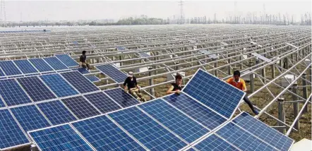  ??  ?? Workers installing solar panels on the ground of an aquatic farm in eastern China’s Zhejiang province. China has been taking steps to encourage cleaner and less polluting sources of power. — AP