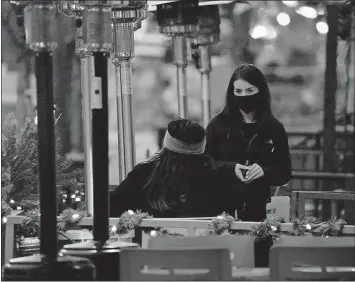  ??  ?? A server wears a face mask Dec. 28 while tending to a patron sitting in the outdoor patio of a sushi restaurant in downtown Denver. Restaurant­s devastated by the coronaviru­s outbreak are getting a lifeline from the pandemic relief package awaiting final approval in the House. [DAVID ZALUBOWSKI/ASSOCIATED PRESS FILE PHOTO]