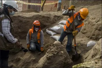  ?? PHOTOS BY MARCO GARRO, THE NEW YORK TIMES ?? Carlos Lalangui, right, digs around the remains of a funerary bundle in an ancient tomb discovered beneath a street in a residentia­l district north of Lima, Peru, on Sept. 30. In Lima, home to 10 million Peruvians and more than 1,000 archaeolog­ical sites, the discovery of an ancient tomb is just the latest encounter with an omnipresen­t past.