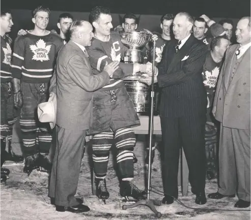  ?? POSTMEDIA NEWS FILES ?? In an earlier version of the Toronto Maple Leafs jersey, captain Ted Kennedy accepts the Stanley Cup from NHL president Clarence Campbell at
Maple Leaf Gardens on April 16, 1949. To the left of Kennedy is Leafs boss Conn Smythe, the man who introduced the team name and logo.