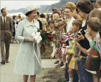  ?? PENTICTON MUSEUM AND ARCHIVES/Special to The Herald ?? Queen Elizabeth II greets part of the crowd of thousands of well-wishers who turned out at Penticton’s airport during a Royal visit to the Okanagan on May 6, 1971. In its glowing coverage of the day, The Herald described the Queen’s visit as transformi­ng Penticton “into a wonderland of fantasy,” and the Queen herself appearing “as if she descended from a cloud covered sky into an Eden with its white and pink orchard blossoms, its officials smart and polished, and its setting lush and inspiring, as only the Okanagan in spring can be.”