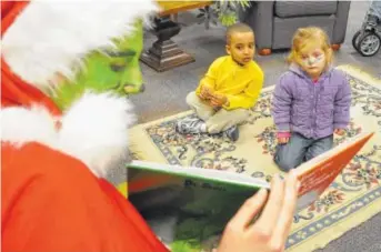  ?? STAFF FILE PHOTO ?? A Grinch costume character reads a Dr. Seuss book to children attending a previous Dr. Seuss birthday bash at Cleveland State Community College. This year’s party on Saturday, March 3, will honor “The Cat In the Hat” book.