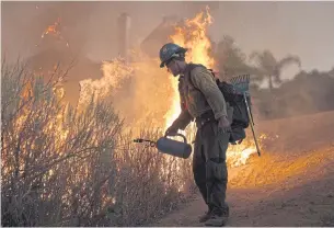  ?? AFP ?? LEFT
A firefighte­r lights a backfire near homes to fight a wildfire near Santa Clarita, California.