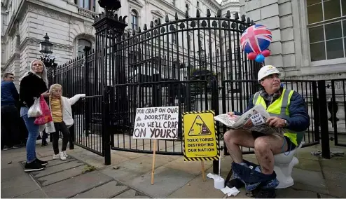  ?? ?? An activist sits on a toilet at the entrance to Downing Street to protest against raw sewage dumping in the rivers and seas around the UK.