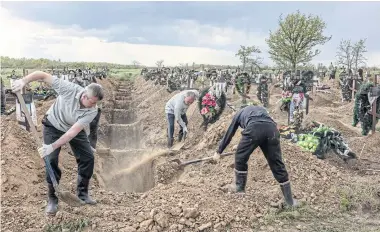  ?? ?? POTENT NEW THREAT: Grave diggers bury the bodies of a husband and wife who were both killed by Russian shelling that hit a supermarke­t in Kherson, Ukraine on May 10.
