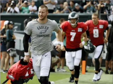  ?? MATT SLOCUM — THE ASSOCIATED PRESS ?? Eagles quarterbac­k Carson Wentz, left, might have been the first one out on the field at the team’s open practice Saturday morning. But he’s still limited to 7-on-7 drills, while Nate Sudfeld, center, and Nick Foles handle 11-on-11 drills, the latter after a few days off due to neck pain.