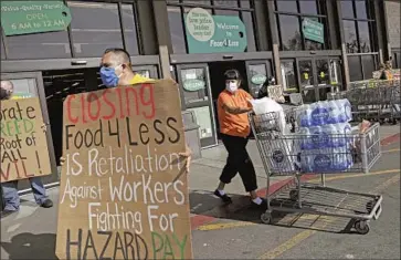  ?? Christina House Los Angeles Times ?? IN RESPONSE to “hero pay” mandates, the grocery store industry has been shutting down stores and suing cities. Above, supporters of a pay increase outside a Food4Less in Long Beach that is slated to be closed.