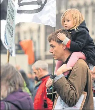  ?? Pictures: TONY SAPIANO ?? DARK FUTURE: A demonstrat­or carries a young child in Whitehall yesterday