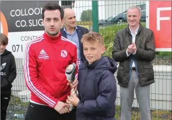  ??  ?? Stephen Healy presents player of the tournament award to Ballina Town’s Oisín Tighe.