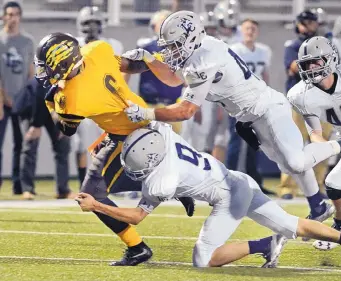  ?? JIM THOMPSON/JOURNAL ?? The Cougars’ Kazy Martin finds little running room as he is dragged down by La Cueva’s Derek Loidolt and Hunter Cardiff during Wednesday night’s game at Community Stadium.