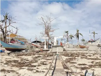  ?? Mat thew Fisher /Postmedia News ?? Devastatio­n surrounds a battered sign welcoming visitors to the Filipino island of Olotayan. Typhoon Haiyan destroyed most of the community’s fishing boats and 260 of its 280 homes.