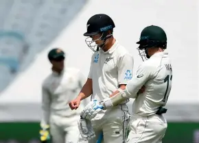  ?? PHOTOSPORT ?? Trent Boult inspects his injured right hand with Australian wicketkeep­er Matthew Wade looking on yesterday.