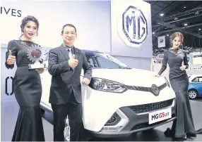  ??  ?? Pongsak Lertrudeew­attanavong, vice-president of MG Sales Thailand, poses with models next to new MG model GS Sport SUV, offered with 1.5 and 2.0 turbo engines.