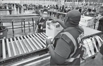  ?? TIMOTHY D. EASLEY, POOL/AP PHOTO ?? The first box containing the Johnson & Johnson COVID-19 vaccine heads down the conveyor to an awaiting transport truck Monday at the McKesson facility in Shepherdsv­ille, Ky.