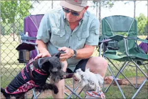  ?? Diane Wagner ?? Jeff Shope introduces two Schnauzers to each other Sunday during the Northwest Georgia Schnauzer Club playdate at the Rome dog park in Ridge Ferry Park.