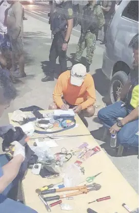  ?? PHOTOGRAPH BY MARIO SUPNAD FOR THE DAILY TRIBUNE ?? MEMBERS of the Police Regional Office in Region 1 present seized items from arrested robbery suspects in a checkpoint at Candon City, Ilocos Sur.