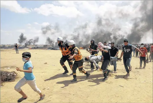  ?? AP PHOTO ?? Palestinia­n medics and protesters evacuate a wounded youth during a protest Monday at the Gaza Strip’s border with Israel, east of Khan Younis, Gaza Strip.