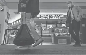  ?? HOFFMAN / MILWAUKEE JOURNAL SENTINEL MARK ?? Travelers pass The Great American Bagel Bakery, one of two new eateries in Concourse D, Wednesday at Mitchell Internatio­nal Airport in Milwaukee.