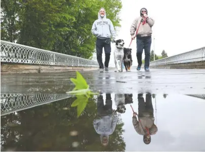  ?? STAFF PHOTO BY TIM BARBER ?? Dave and Wendy Rhead, of Beaverton, Ontario, walk their dogs, Jezzie and Jasper, across the Walnut Street Bridge early Monday. “We started back home too soon,” Wendy Rhead said. “We left Brownsvill­e, Texas, too early. We’ve been in shorts all winter,”...