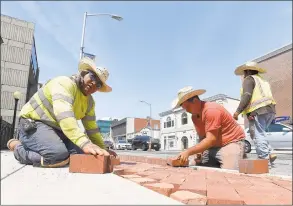  ?? Matthew Brown / Hearst Connecticu­t Media ?? Rafael Cruz and Simone Rossi lay bricks that are part of a decorative edging to a new sidewalk along Summer Street in Stamford on Tuesday. The crew from Colonna Concrete and Asphalt Paving, out of West Haven, wore large straw caps to help shade themselves from the sun. Temperatur­es in the region have reach into the 90s with no immediate relief expected.