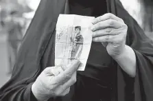  ?? Khalid Mohammed, The Associated Press ?? A woman holds a picture of her missing son during an antigovern­ment protest in February in Baghdad. Fifty- three demonstrat­ors remain missing since historic protests began in October 2019 about corruption and the ruling class in Iraq.