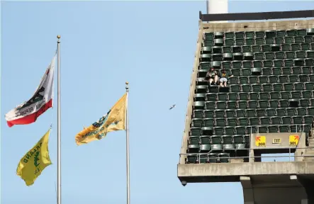  ?? Photos by Scott Strazzante / The Chronicle ?? Above, two A’s fans enjoy the view from the upper deck of the Coliseum during Sunday afternoon’s game against the Tigers. Below, Jeremy Starnes, son Aidan, 10 (right), and Dylan Blackmon, also 10, look over the field before the game.