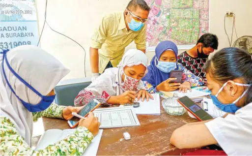  ?? ALFIAN RIZAL/JAWA POS ?? KANTOR PLUS TEMPAT BELAJAR: Lurah Pucang Sewu Kenny Pieter Tupamahu (tengah) memantau kegiatan belajar daring siswa di kantor kelurahan kemarin pagi.