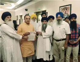  ?? — PTI ?? The head priest of the Damdami Taksal, Gyani Harnam Singh Khalsa, submits a memorandum to BJP leader Subramania­n Swamy in New Delhi on Thursday.