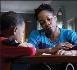  ?? (AP/Mark Humphrey) ?? Ensrud helps her son, Christian with his homework Nov. 21 at their home in Nashville.