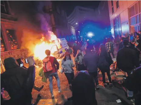  ?? Reuters ?? Demonstrat­ors watch a police vehicle go up in flames during the violent protests in Bristol