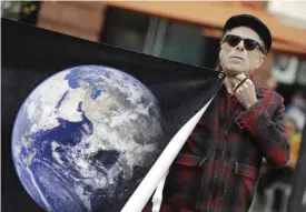  ??  ?? SAN FRANCISCO: Kurt Wechsler holds an image of the earth during a rally by scientists in conjunctio­n with the American Geophysica­l Union’s fall meeting in San Francisco. The rally was to call attention to what scientists believe is unwarrante­d attacks...