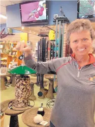  ?? ROSALIE RAYBURN/JOURNAL ?? Wild Birds Unlimited store owner Mary Schmauss holds a feeder containing a cylinder of tightly compacted seeds and nuts that is useful to put out if you are going to be away. It will last a long time and the seeds and nuts won’t make a mess on the...