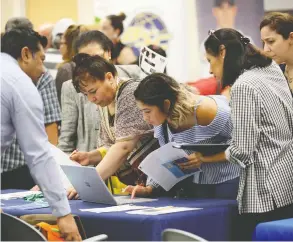  ?? LYNNE SLADKY / THE ASSOCIATED PRESS FILES ?? Applicants this week look at what’s available at a job fair in Miami.