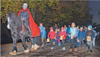  ?? FOTO: SUSI DONNER ?? „…hoch oben leuchten die Sterne…“: Der Soldat Martin (Gabriele Kleinhans) führt den Martinsumz­ug in Hergenswei­ler auf seinem braven Pferd Dano an.