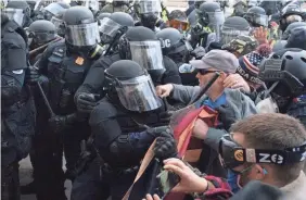  ?? JOSE LUIS MAGANA/AP ?? Capitol Police officers in riot gear push back demonstrat­ors who try to break a door of the U.S. Capitol on Jan. 6 in Washington.